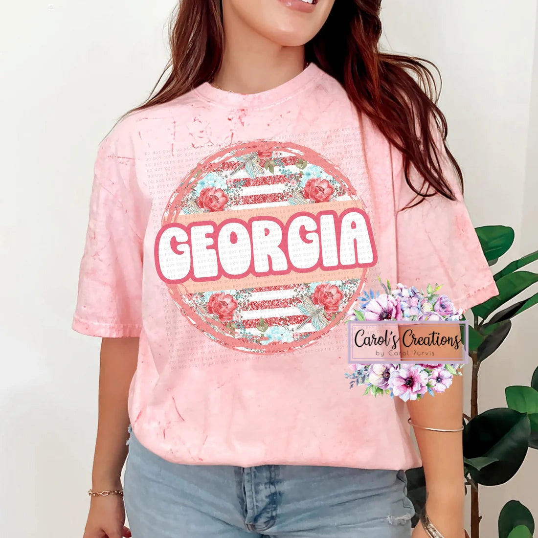 Person wearing a pink t-shirt with 'Georgia' design, standing against a white background.