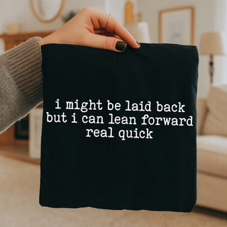 Person holding a black pillow with humorous text in a living room setting