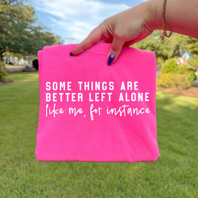 Hand holding a pink sign with text outdoors