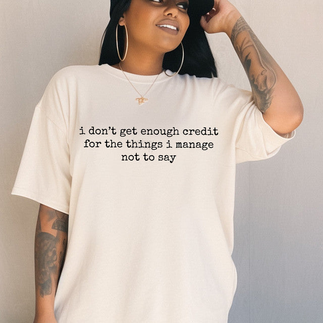 Person wearing a white t-shirt with text, standing against a plain background