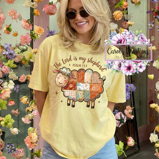 Person wearing a yellow t-shirt with a colorful sheep graphic and text, surrounded by floral decorations.