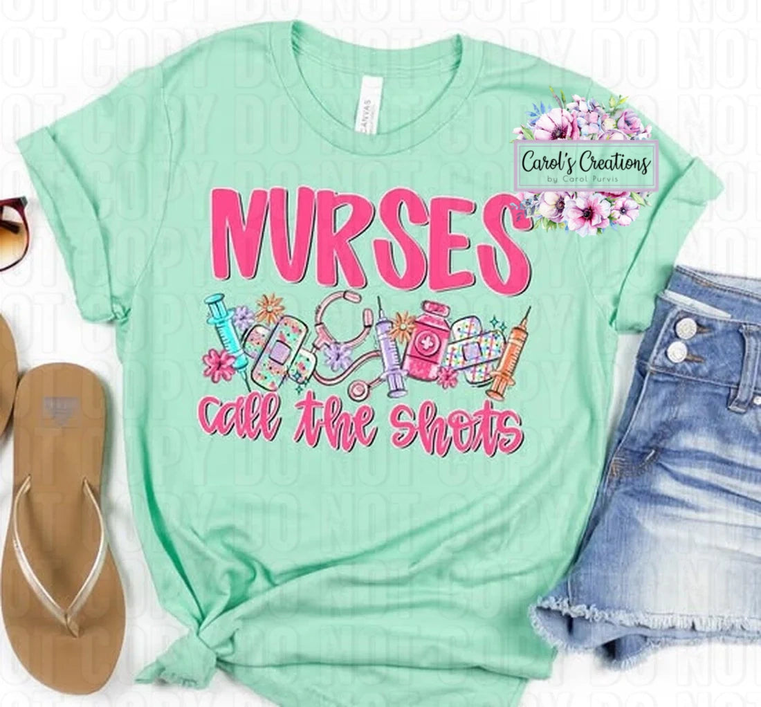 Mint green t-shirt with 'Nurses call the shots' text and medical-themed graphics, displayed with sandals and shorts.