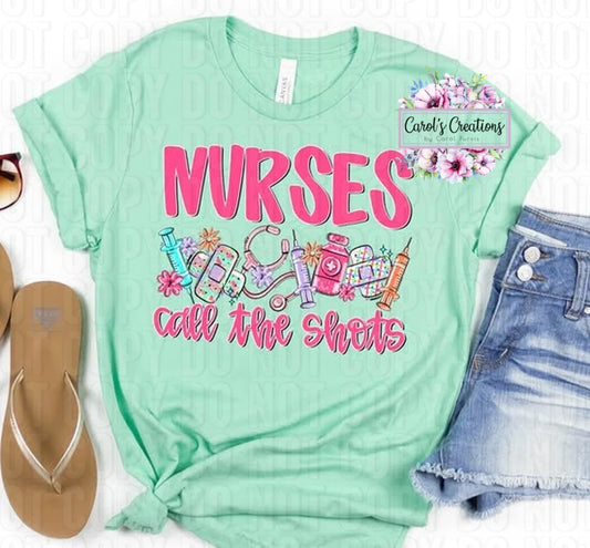 Mint green t-shirt with 'Nurses call the shots' text and medical-themed graphics, displayed with sandals and shorts.