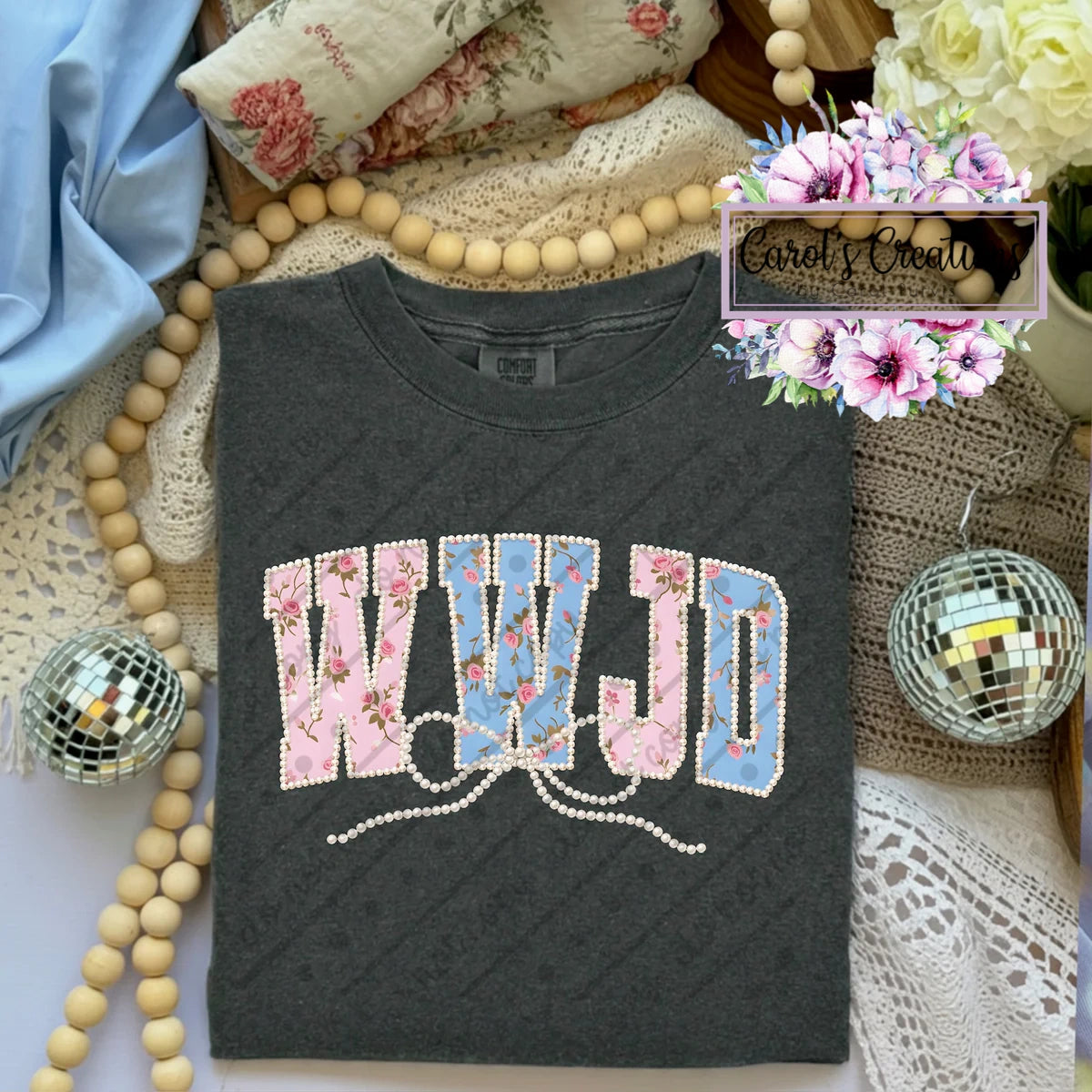 Black t-shirt with floral and rhinestone design on a decorative background