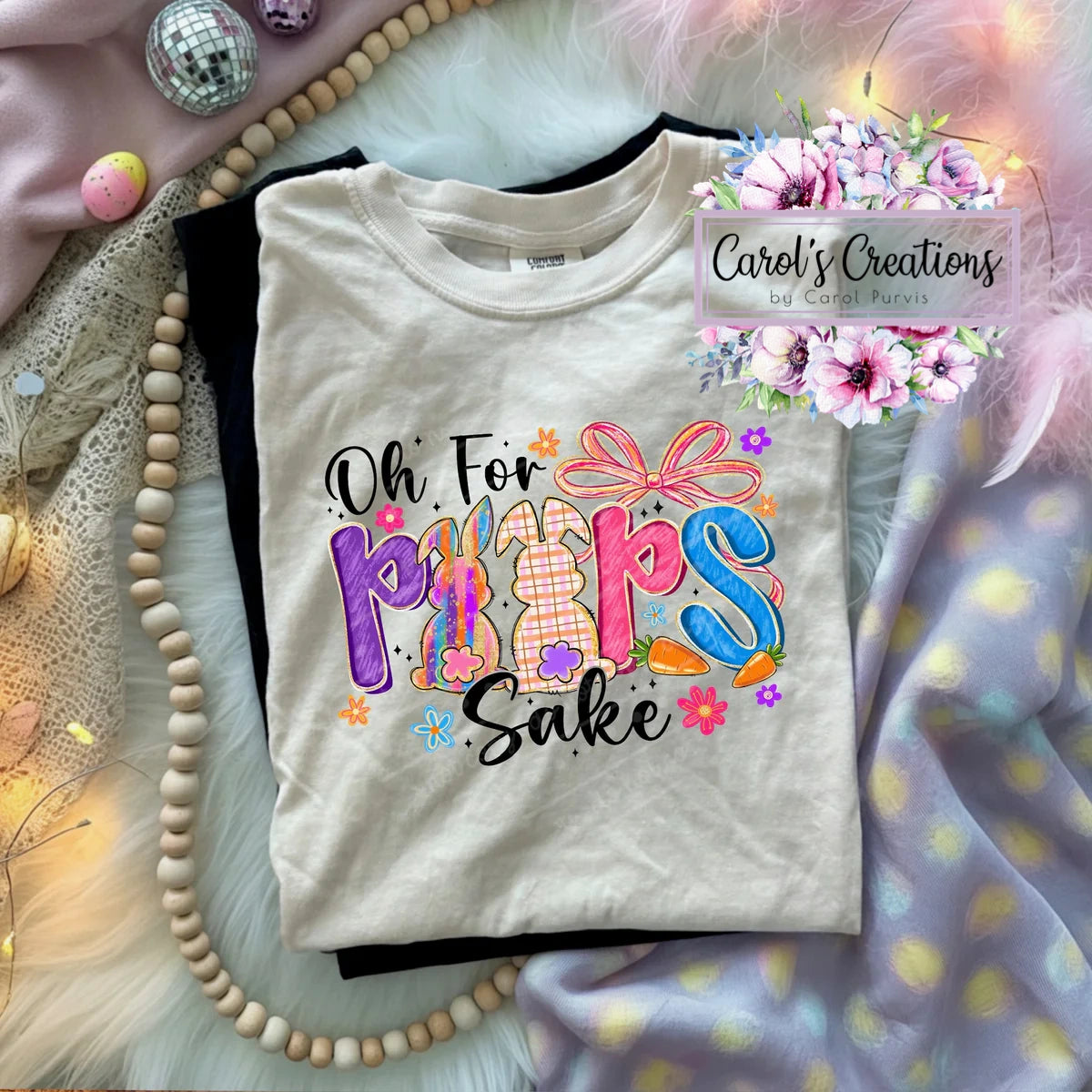 Beige t-shirt with colorful text design on a textured surface with decorative elements.