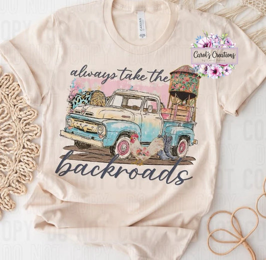 Beige t-shirt with a graphic of a truck and text 'always take the backroads' on a white background.