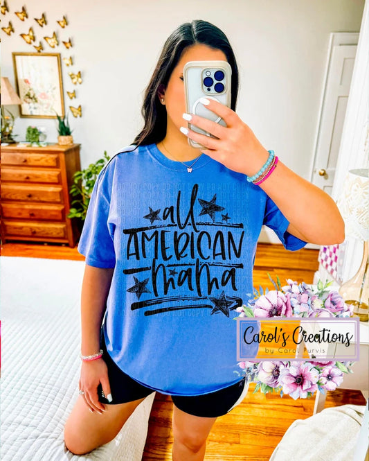 Woman wearing a blue t-shirt with 'All American Mama' text, taking a mirror selfie in a room.