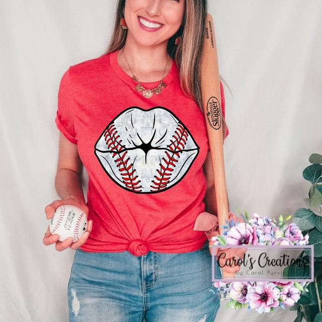 Woman wearing a red t-shirt with a baseball-themed graphic, holding a baseball, against a plain background.
