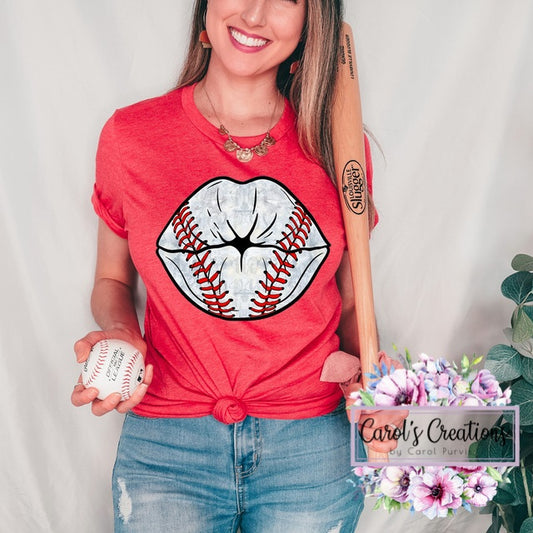 Woman wearing a red t-shirt with a baseball-themed graphic, holding a baseball, against a plain background.