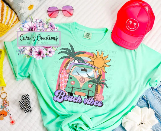 Mint green t-shirt with 'Beach vibes' design, surrounded by accessories on a white surface.