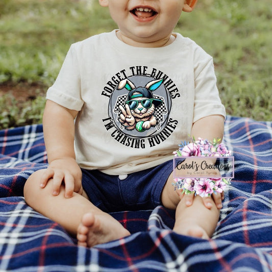Child wearing a t-shirt with a graphic design of a cat and text, sitting on a plaid blanket outdoors.