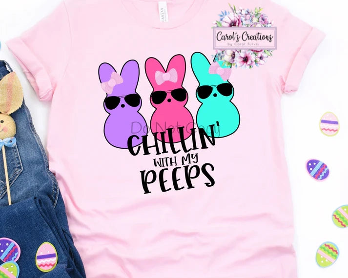 Pink t-shirt with colorful bunny design and text 'Chillin' with my peeps' on a white background.