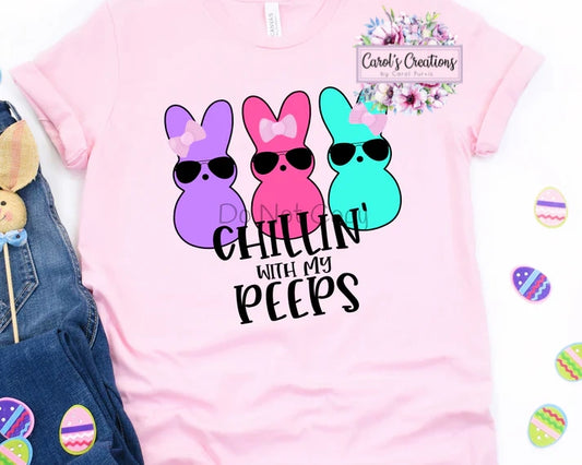 Pink t-shirt with colorful bunny design and text 'Chillin' with my peeps' on a white background.