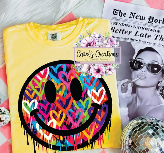 Yellow t-shirt with colorful smiley face design on a surface with a magazine and disco balls.