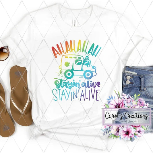 White t-shirt with colorful graphic and text on a white background with flip-flops and jeans.