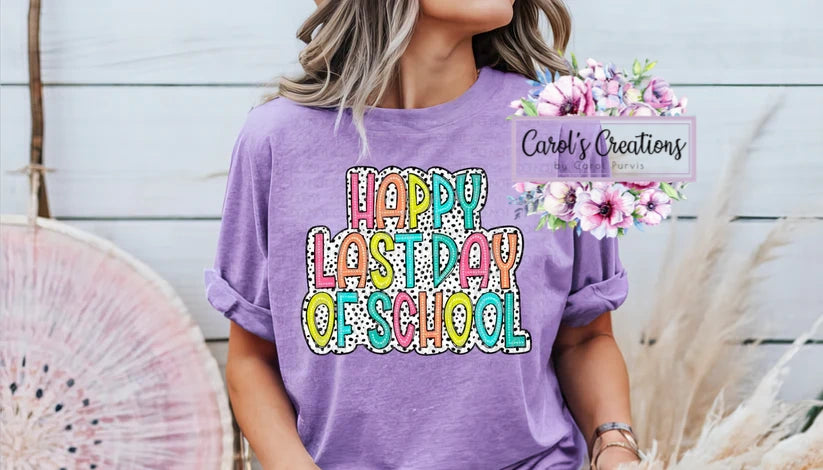 Person wearing a purple t-shirt with 'Happy Last Day of School' text, standing against a light wooden background.