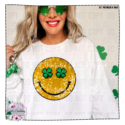 Person wearing a white sweatshirt with a smiley face design featuring clovers, on a light background with shamrock patterns.