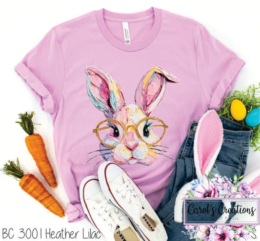 Pink t-shirt with a colorful bunny graphic, carrots, and denim jeans on a white background.