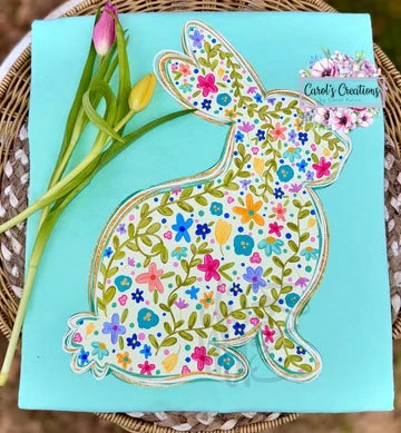 Floral-patterned bunny design on a blue card with tulips on a woven surface