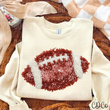 Beige sweatshirt with a red and white football design on a wooden surface.