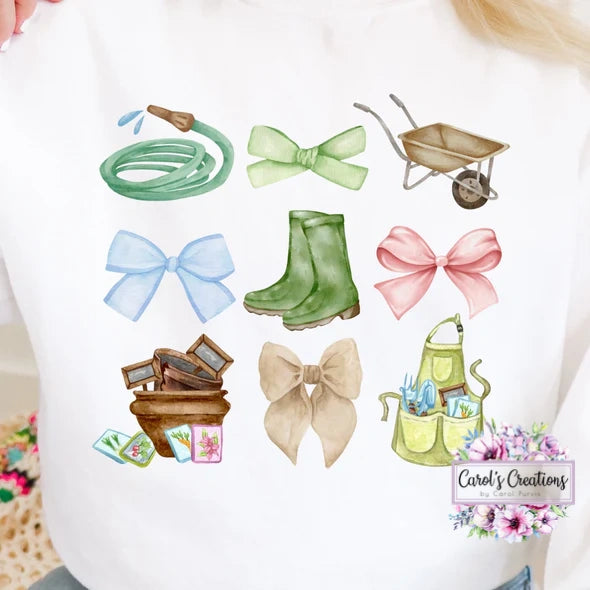 White shirt with gardening-themed illustrations including a hose, wheelbarrow, boots, and bows.