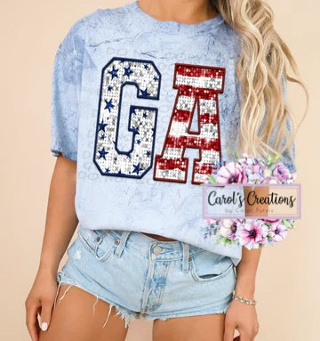 Person wearing a light blue distressed t-shirt with 'GA' design, standing against a beige background.