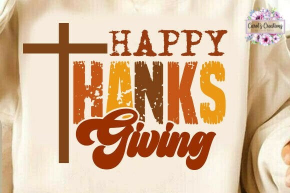 A close-up of a cream-colored garment featuring a distressed Thanksgiving graphic with a brown cross, the words 'HAPPY THANKS Giving' in brown, orange, and yellow tones, and a small 'Carol's Creations' logo in the top right corner.