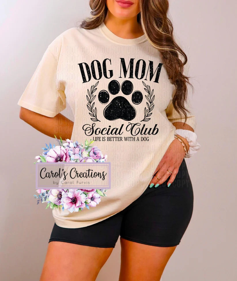 Person wearing a 'Dog Mom Social Club' t-shirt with floral design and text overlay.