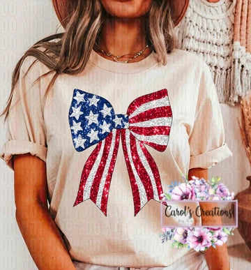 Person wearing a shirt with a large bow design featuring the American flag, with 'Carol's Creations' branding.