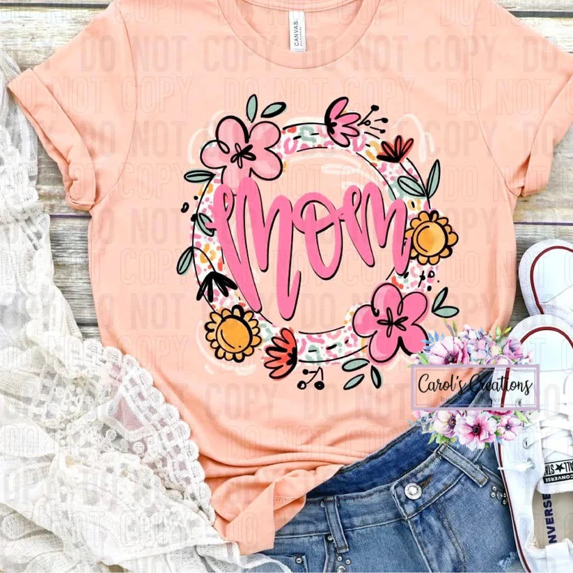 Pink t-shirt with 'mom' design on a wooden surface