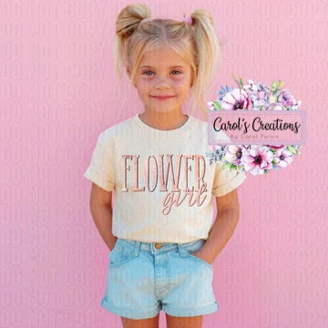 Young girl wearing a 'flower girl' shirt with floral design in the corner on a pink background