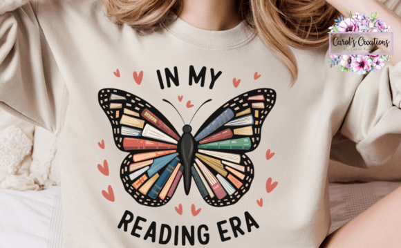 A person wearing a cream-colored sweatshirt with a graphic design that reads 'IN MY READING ERA' around a butterfly made of colorful book spines, with small pink hearts. A 'Carol's Creations' watermark is visible in the top right corner.