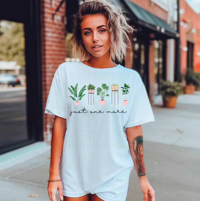 Woman wearing a light blue t-shirt with plant design and text on a city street.
