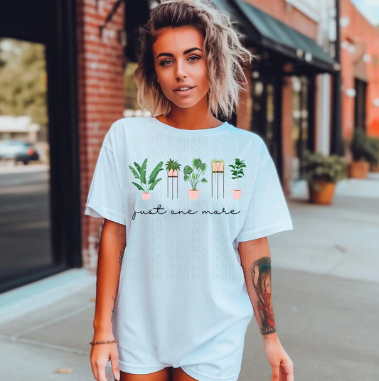 Woman wearing a light blue t-shirt with plant design and text on a city street.