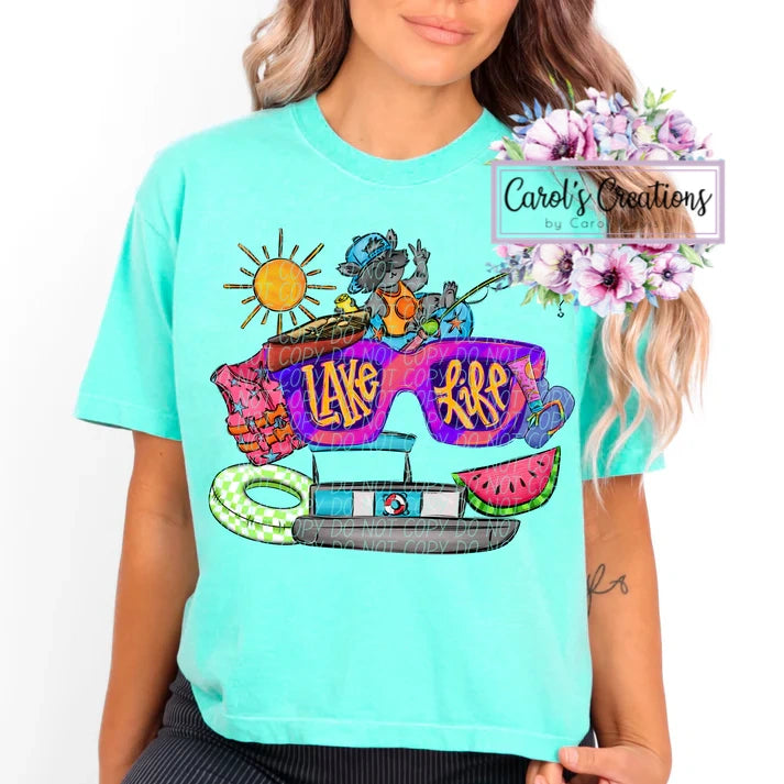 Person wearing a turquoise t-shirt with a colorful graphic design featuring sunglasses and text.
