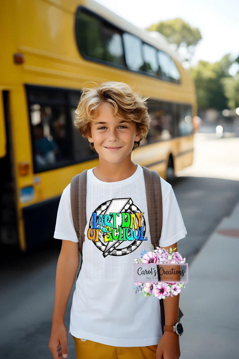 Young boy standing in front of a yellow school bus with a backpack, wearing a white t-shirt with colorful text.
