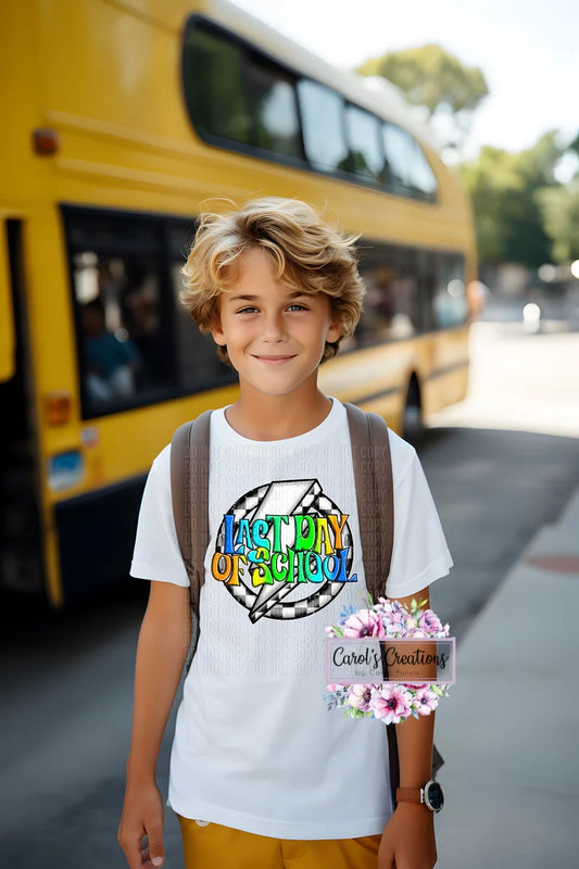 Young boy standing in front of a yellow school bus with a backpack, wearing a white t-shirt with colorful text.