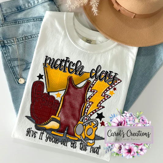 White t-shirt with football-themed graphic and text, displayed with jeans and a hat.
