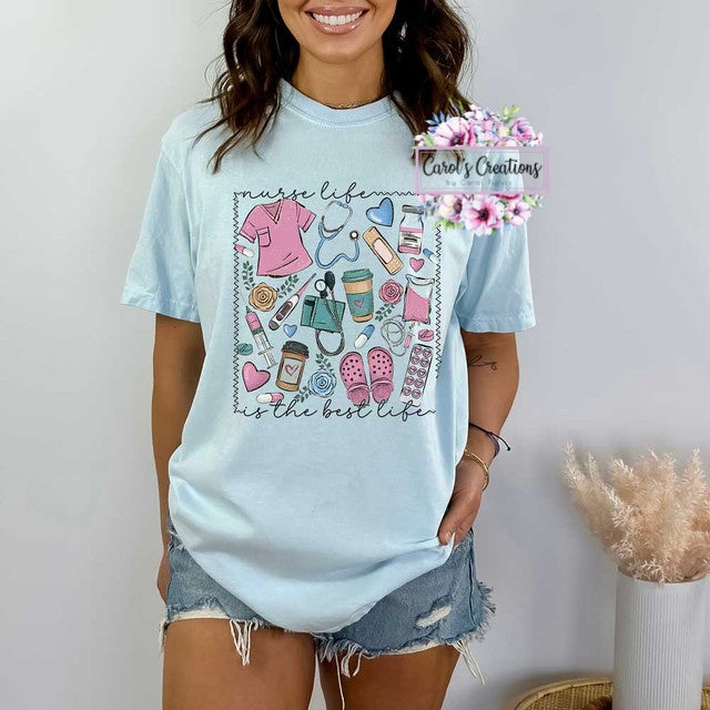 Woman wearing a light blue t-shirt with a graphic design and text, standing against a plain background.