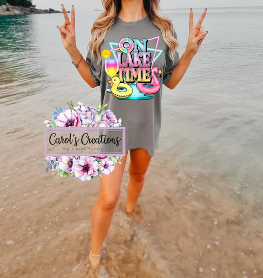 Person wearing a gray t-shirt with colorful text and graphics, standing on a beach.
