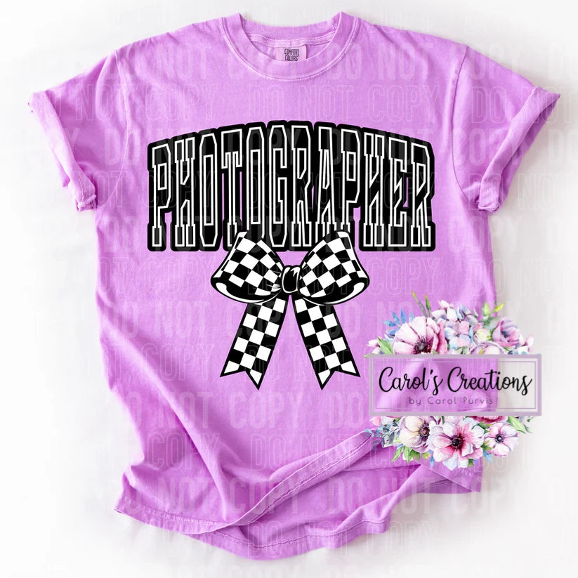 Purple t-shirt with 'PHOTOGRAPHER' text and bow design on a white background