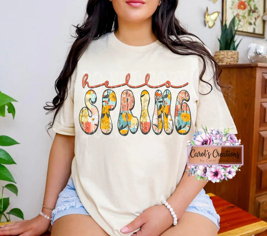 Person wearing a 'Hello Spring' t-shirt with floral text in a home setting