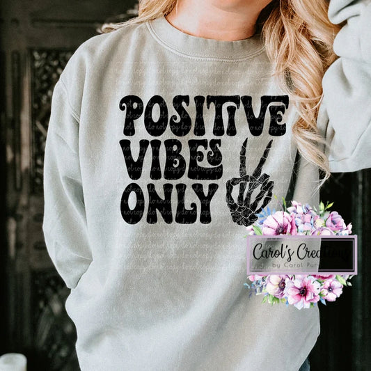 Person wearing a light gray sweatshirt with 'Positive Vibes Only' text and a peace sign.