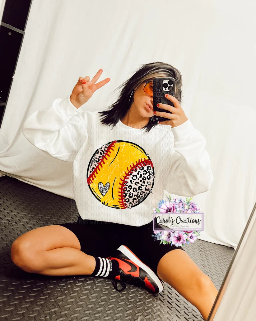 Person wearing a white sweatshirt with a colorful graphic design, sitting on a textured floor.