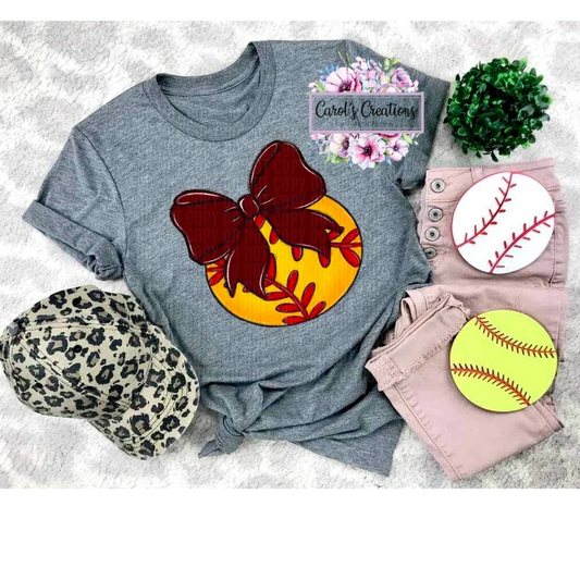Gray t-shirt with a colorful bow design, surrounded by accessories on a textured surface.