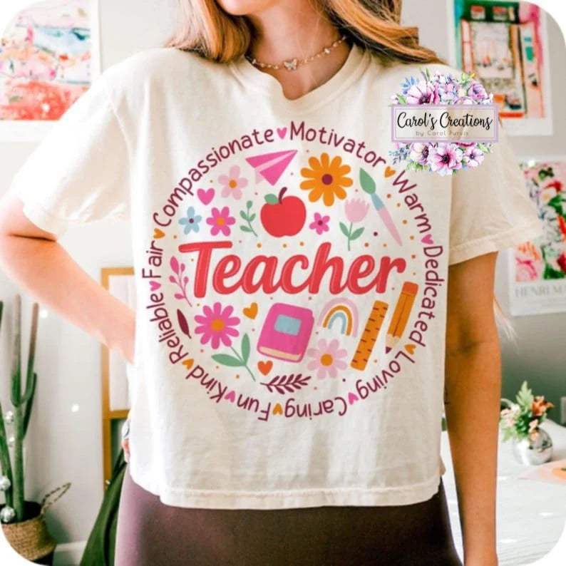 Person wearing a white t-shirt with colorful graphics and text about being a teacher.