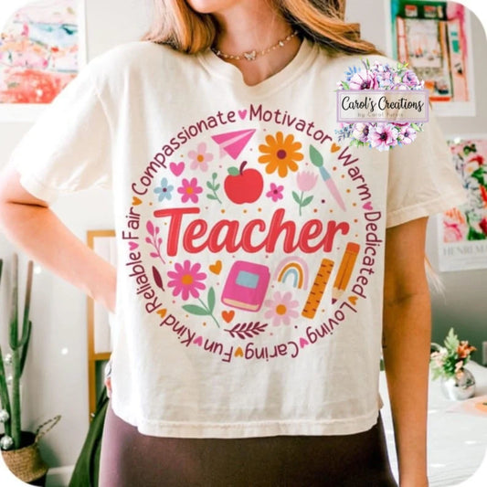 Person wearing a white t-shirt with colorful graphics and text about being a teacher.