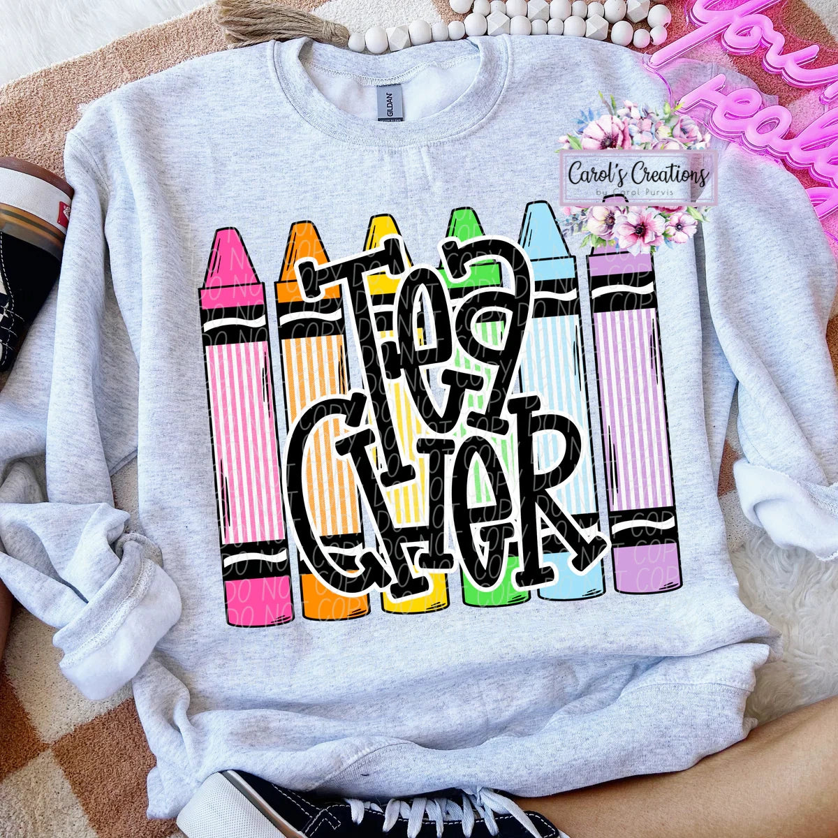 Gray sweatshirt with colorful crayon design and 'Cheer' text, displayed on a surface.