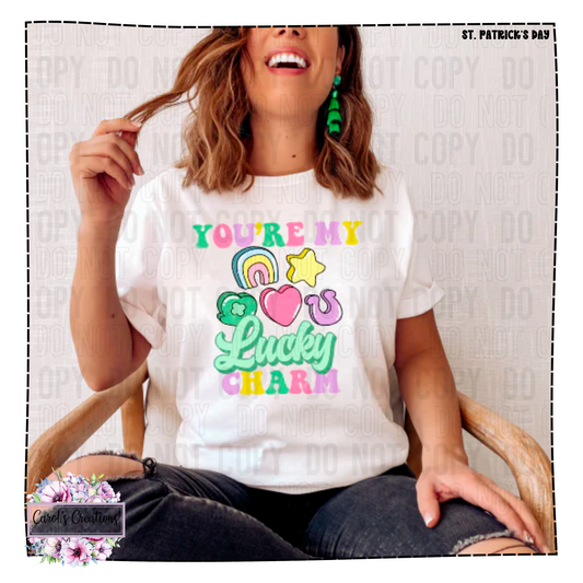 Person wearing a white t-shirt with colorful text and graphics, sitting on a chair.