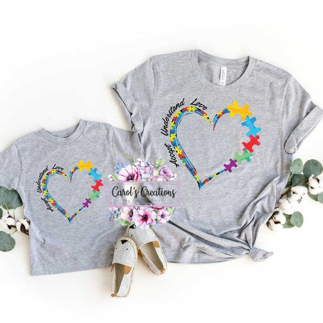 Two gray t-shirts with colorful heart designs and text on a white background.